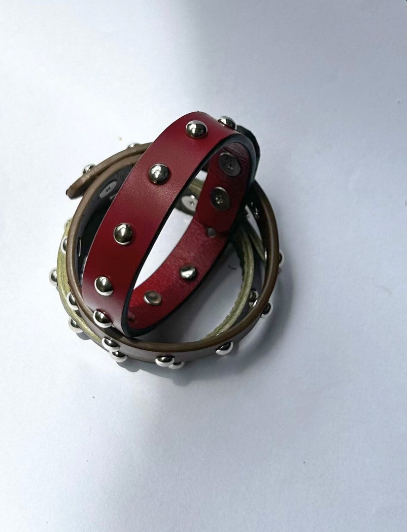 Two studded leather bracelets, one red and one brown, on a white background