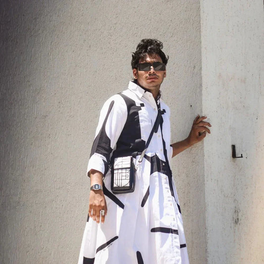 Stylish man wearing black and white graphic long shirt dress and sunglasses posing against textured wall