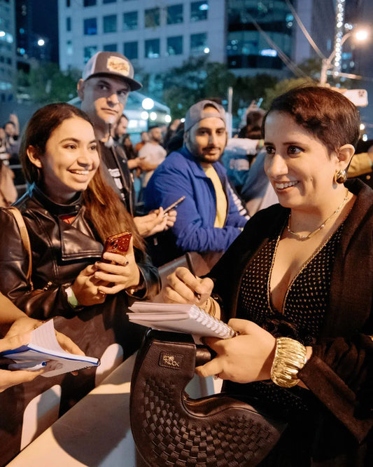 Woman signing autographs and smiling to fans at outdoor night event in city