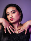 Close-up portrait of woman with red lipstick and gold rings posing against purple background