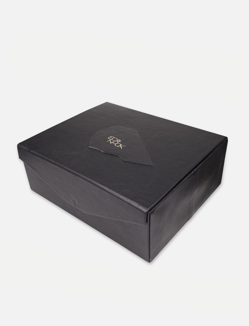 Black textured rectangular gift box with embossed gold logo on lid, white background