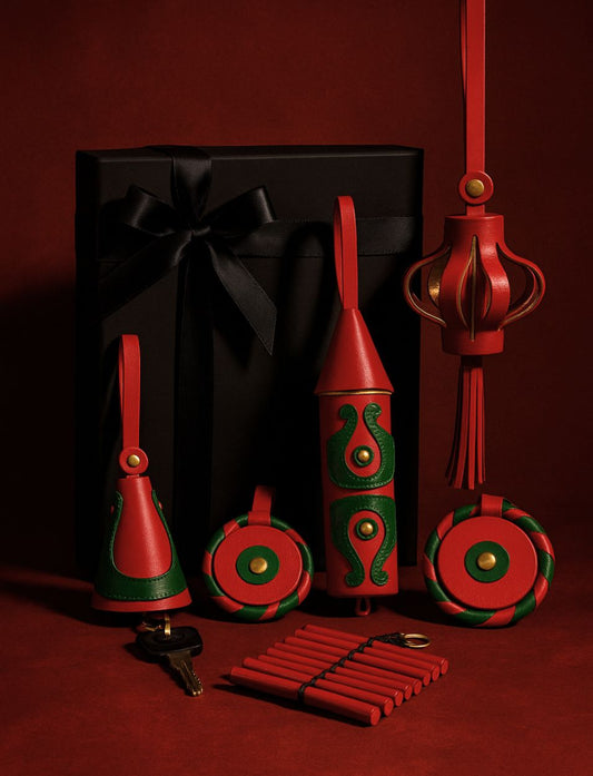 Elegant black gift box with black ribbon alongside red and green leather keychains and decorations on red background