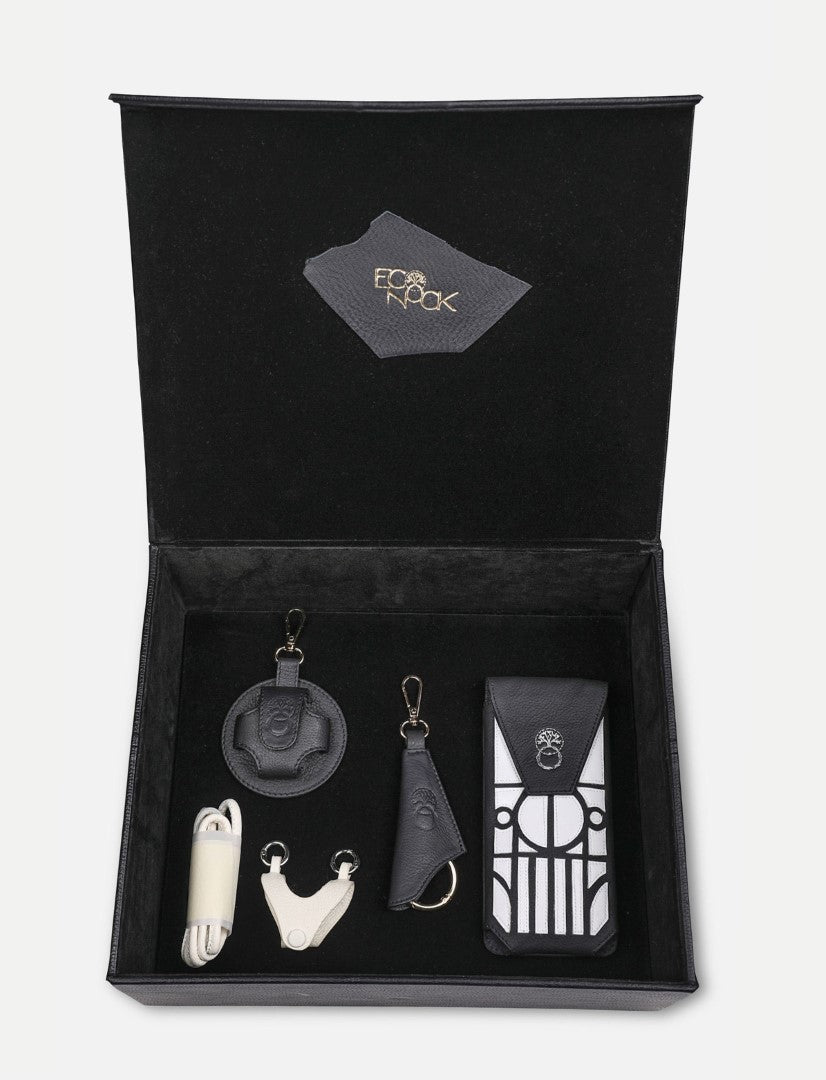 Open black leather gift box with upcycled handcrafted accessories including keychains and a pouch