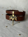 Timeless tan leather upcycled bracelet with gold and black tribal sun pendant on white fabric background