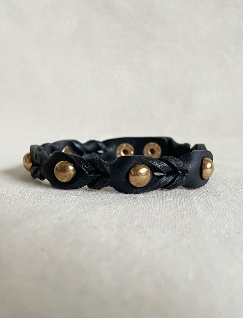 Timeless black leather cuff bracelet with gold metallic studs, handcrafted unisex jewelry on white fabric