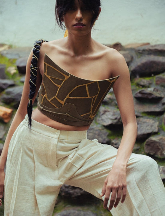 Woman wearing a brown strapless corset top with geometric patterns and cream wide-leg pants outdoors