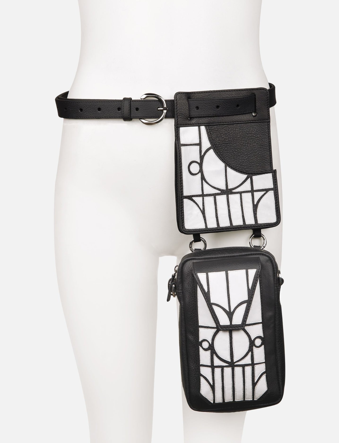 Black leather thigh bag with white geometric applique patterns and adjustable belt on mannequin