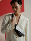 Fashion model wearing ivory blazer and holding black leather crossbody bag with white geometric flap