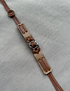 Brown leather strap with metal rings laid on textured gray fabric