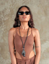 Woman wearing black sunglasses and brown sleeveless top with handmade black leather sunglasses holder necklace