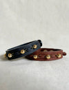 Handcrafted unisex black and brown leather bracelets with gold beads, laid on light fabric background
