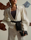 Fashionable woman in white suit with puffy sleeves, embroidered collar, black belt bag and clutch