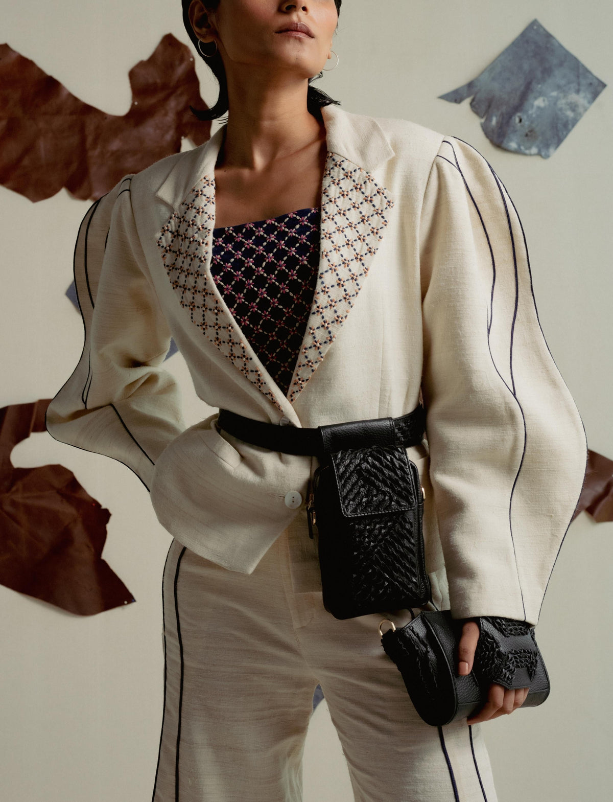 Fashionable woman in white suit with puffy sleeves, embroidered collar, black belt bag and clutch