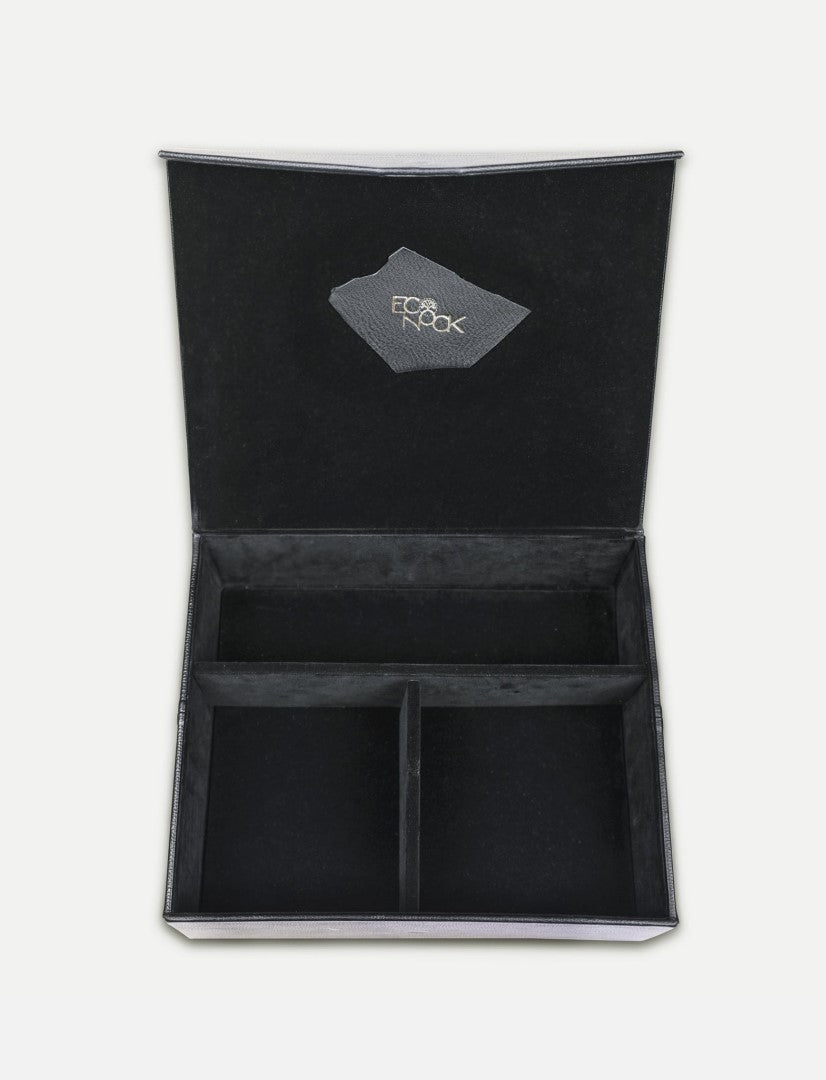 Open black velvet organizer box with three compartments and logo patch inside the lid