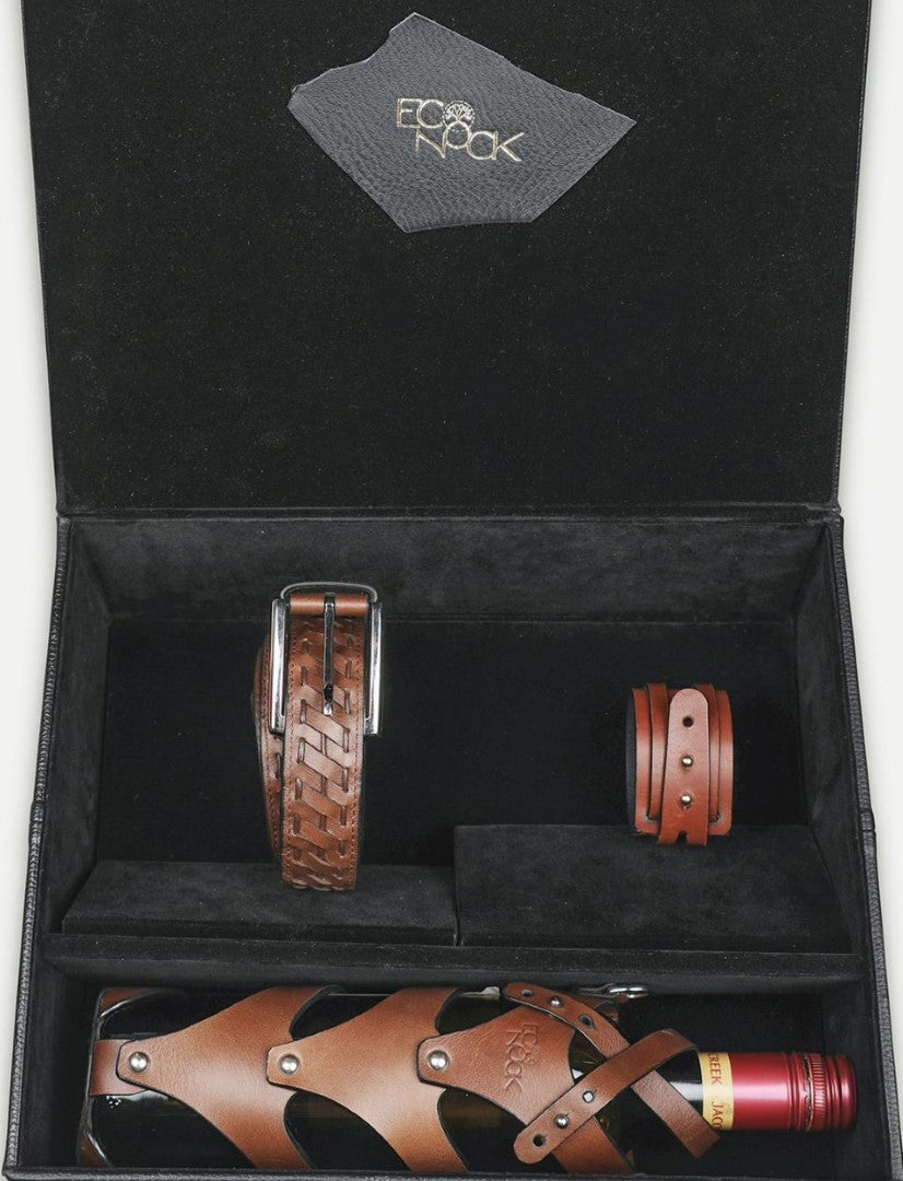 Black gift box with Eco Nook logo containing brown leather belt, bracelet, and leather-covered wine bottle