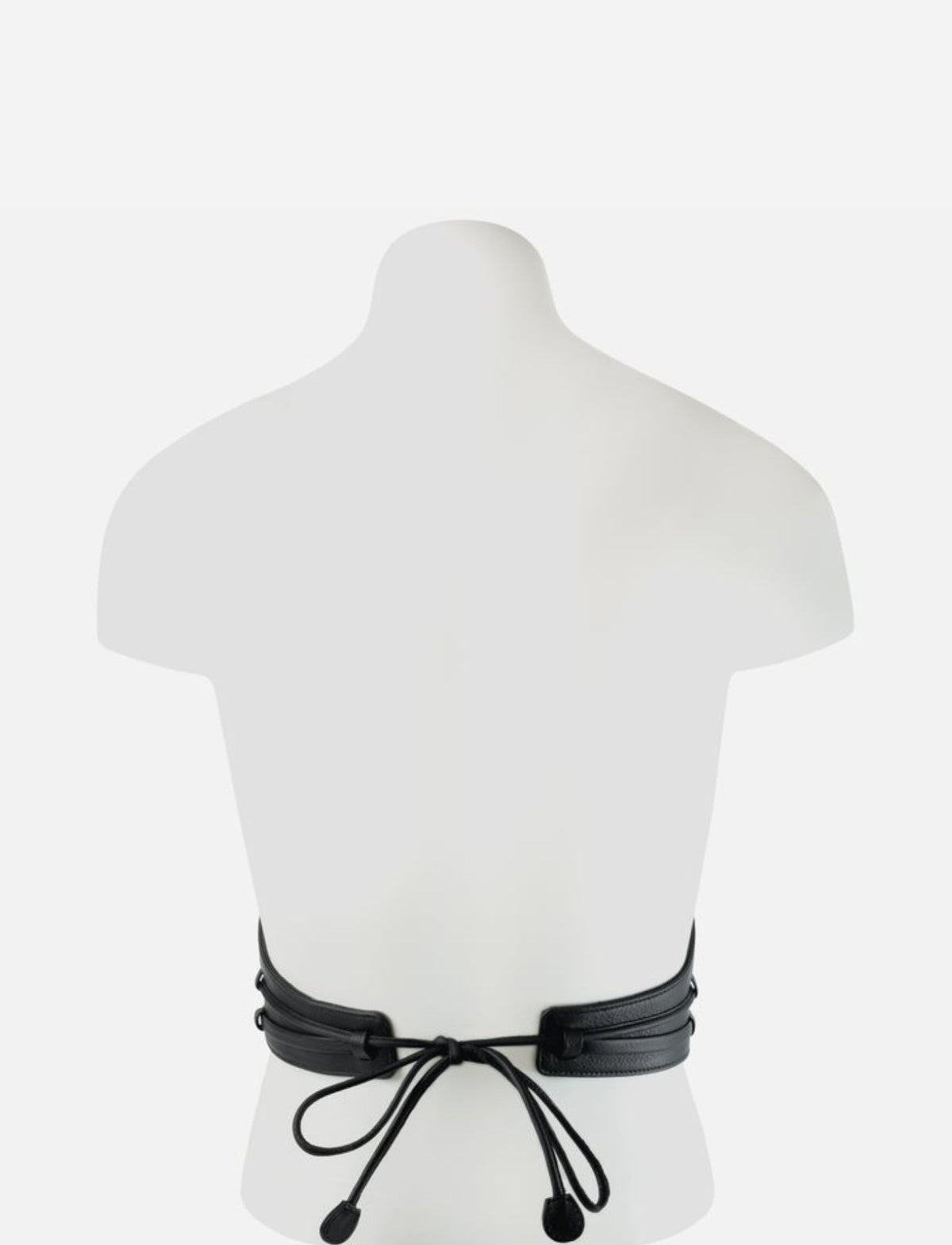 Back view of black leather corset with tied lace-up closure on white mannequin