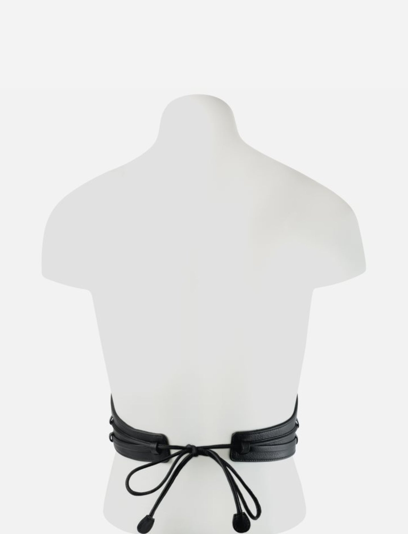 Back view of black leather corset with tied lace-up closure on white mannequin