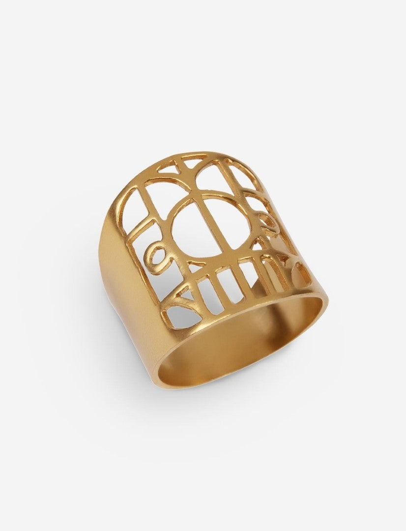 Gold metal ring with intricate geometric cutout pattern on white background