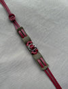 Handmade leather bracelet with burgundy straps and metal rings on gray fabric background