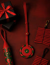 Black gift boxes with red ribbons and red and green leather accessories on dark red background