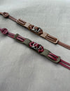 Two handmade leather bracelets with metal ring accents on neutral fabric background
