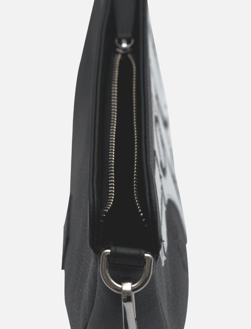 Side view of a black leather sling bag with a silver zipper and metal ring, minimalist design