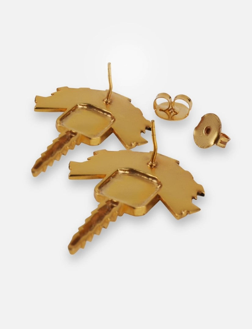 Pair of gold metal earrings shaped like keys with separate butterfly backs on white background