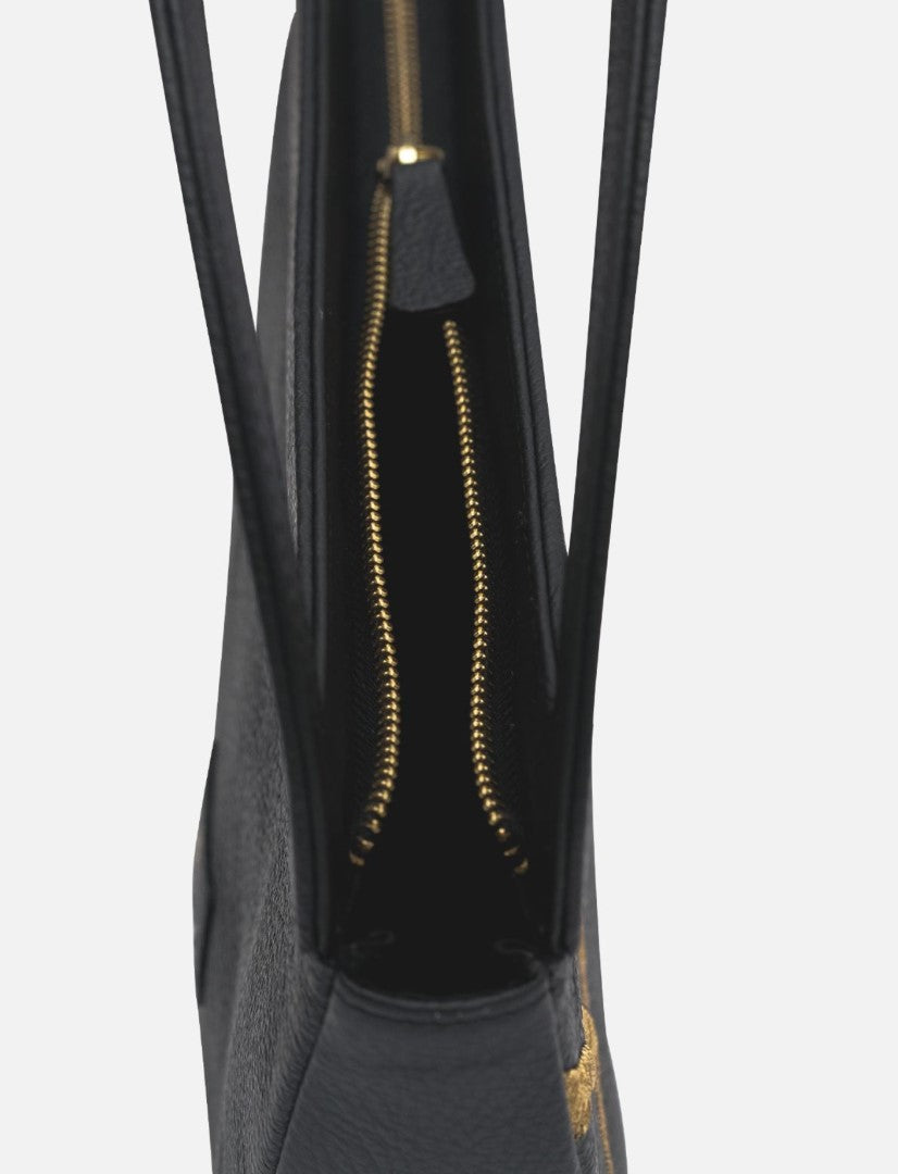 Close-up of black leather clutch bag with gold zipper and slim handles on white background