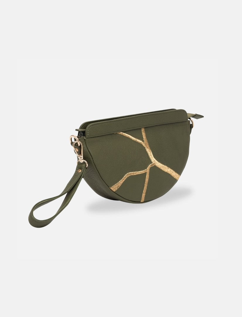Timeless olive green leather sling bag with gold resin crack detail and wrist strap on white background