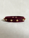 Timeless burgundy leather bracelet with upcycled gold beads and handcrafted stitching on neutral fabric