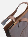 Close-up of brown leather tote bag with gold zipper and sturdy handles on white background