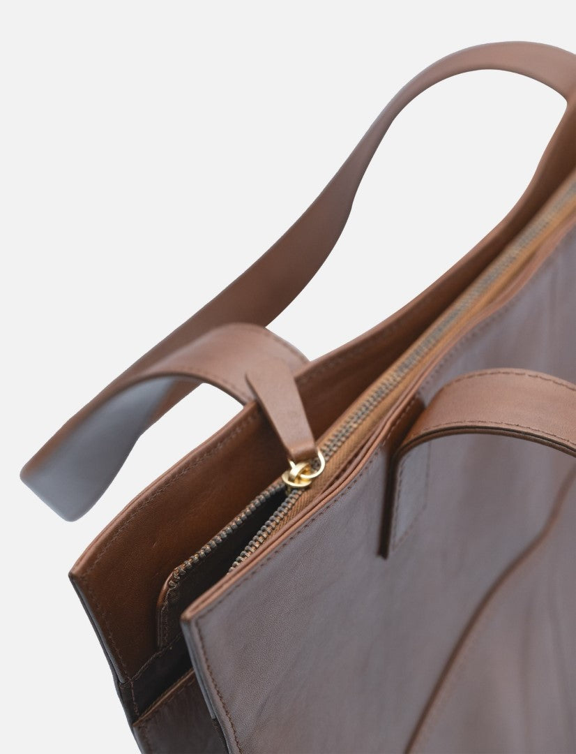 Close-up of handcrafted brown leather tote bag with zipper closure and sturdy handles