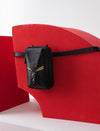 Black leather belt bag with gold wing design on red abstract curved backdrop