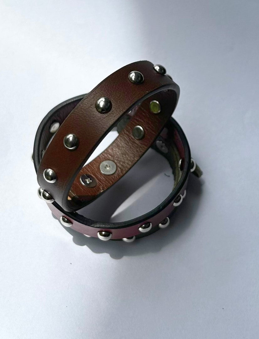 Brown leather bracelet with silver metal studs on white background