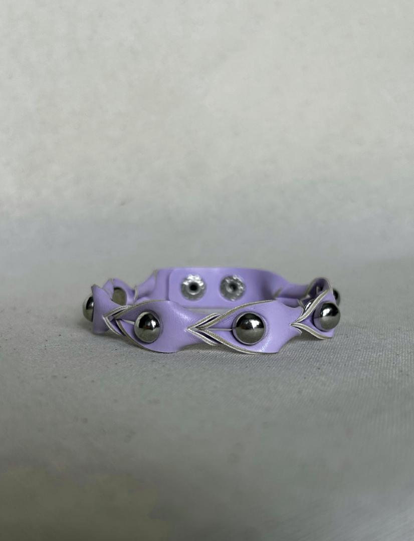Timeless lilac vegan leather cuff bracelet with silver metallic studs on a neutral fabric background