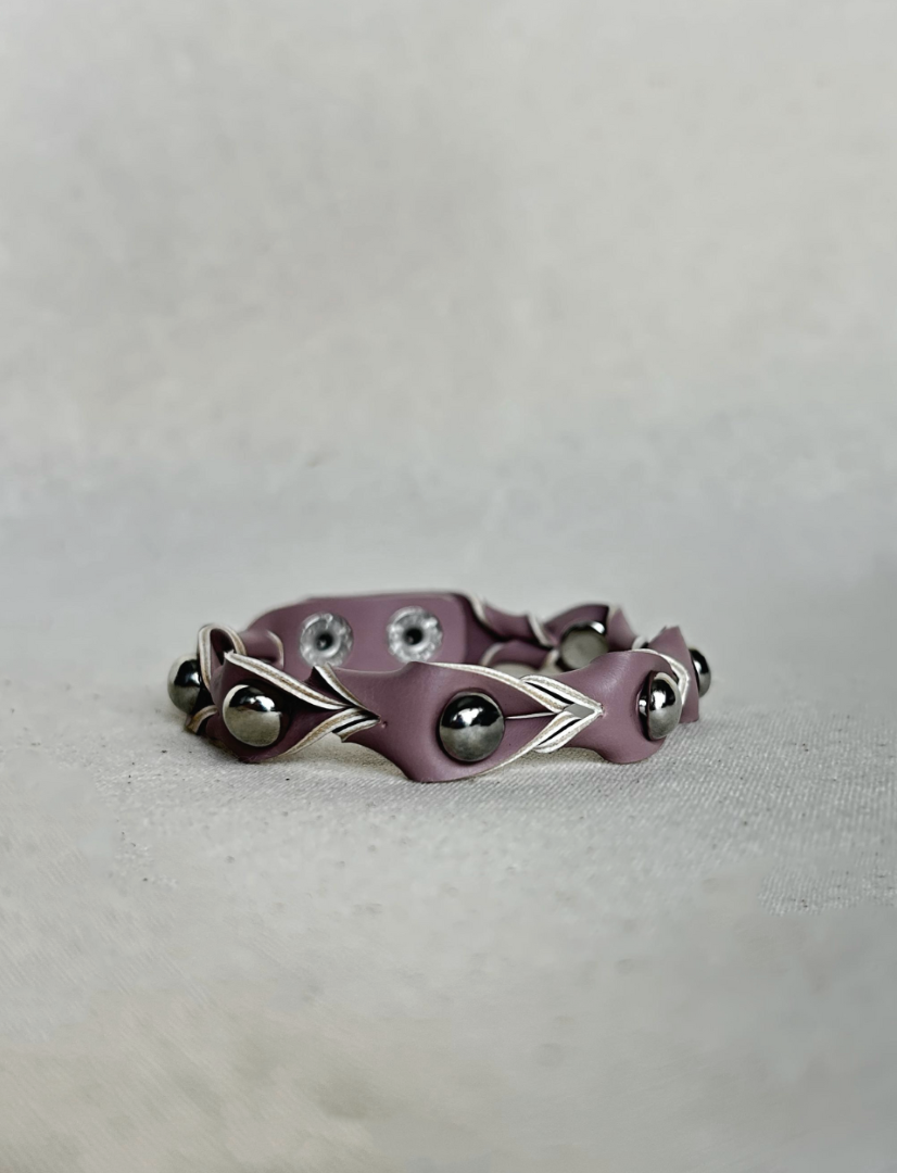 Pink vegan leather bracelet with silver beads and metallic accents on beige fabric