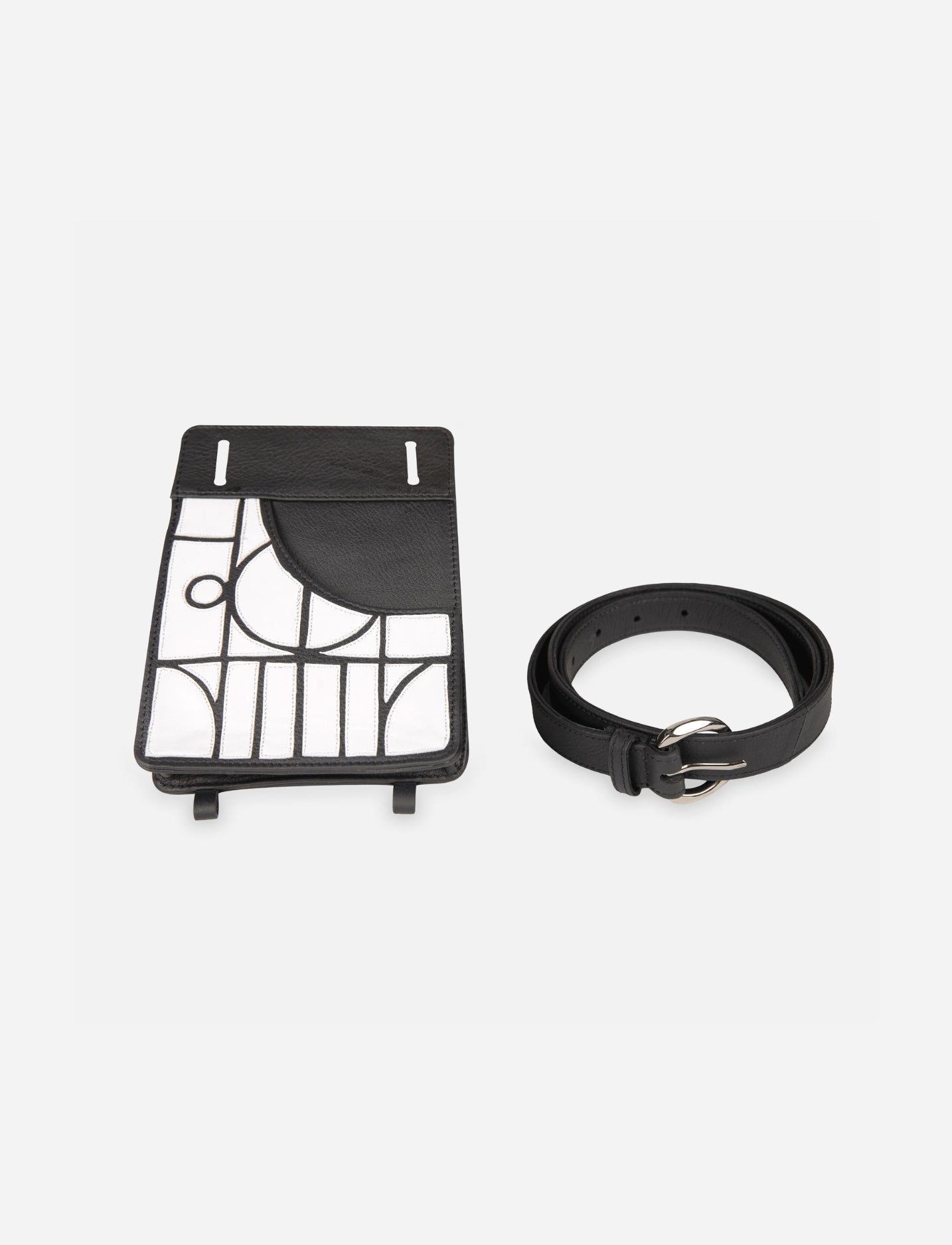 Black leather thigh bag with white geometric applique and matching black leather belt with silver buckle on white background