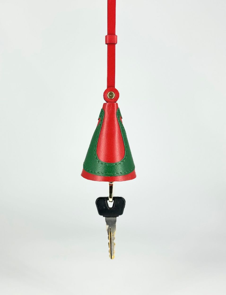 Red and green leather key holder with a hanging strap and a metal key attached