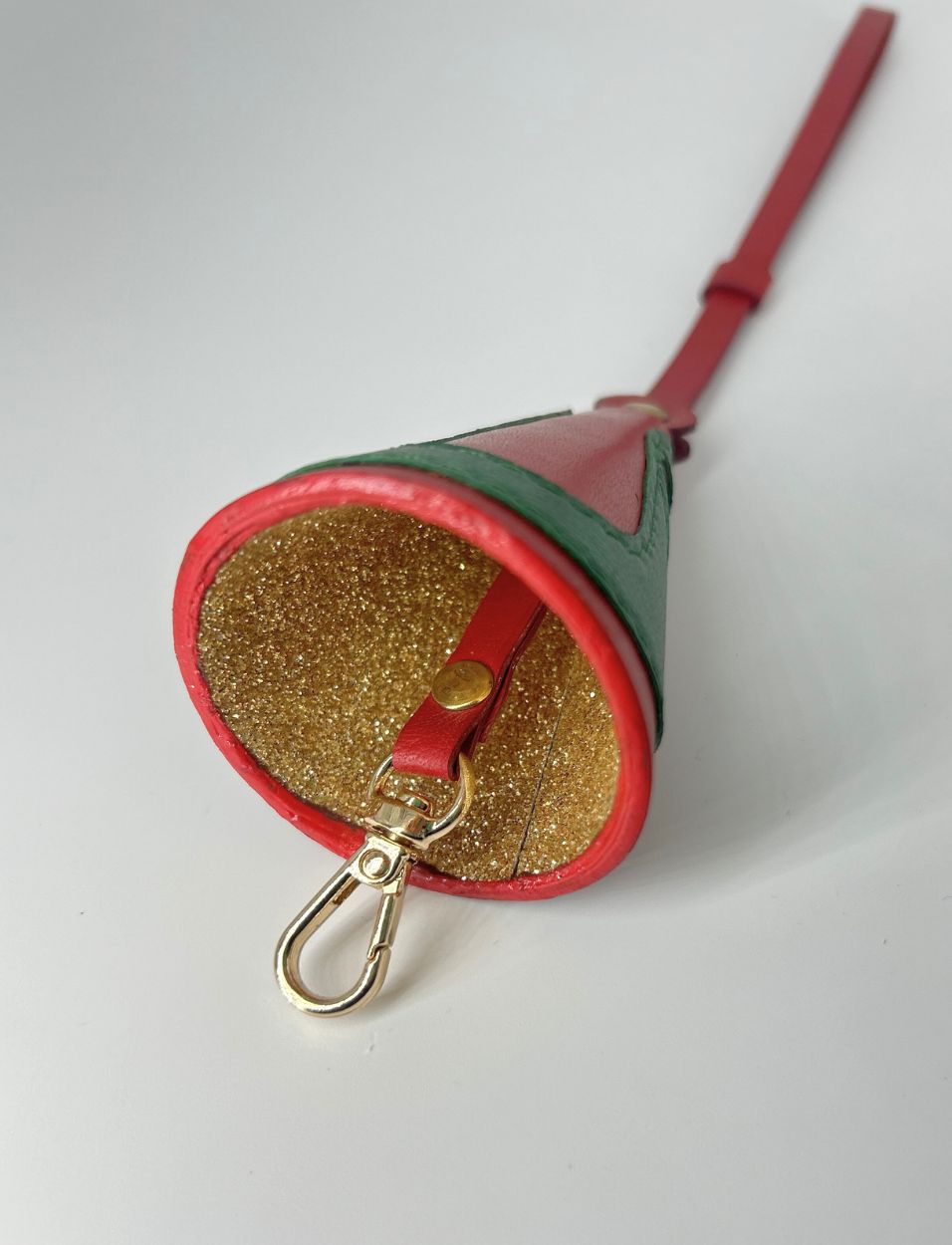 Red and green leather keychain holder with gold glitter interior and gold clasp on white background