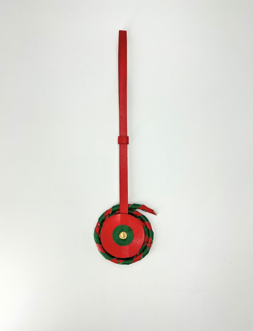 Red leather tag with circular charm featuring green and gold accents on white background