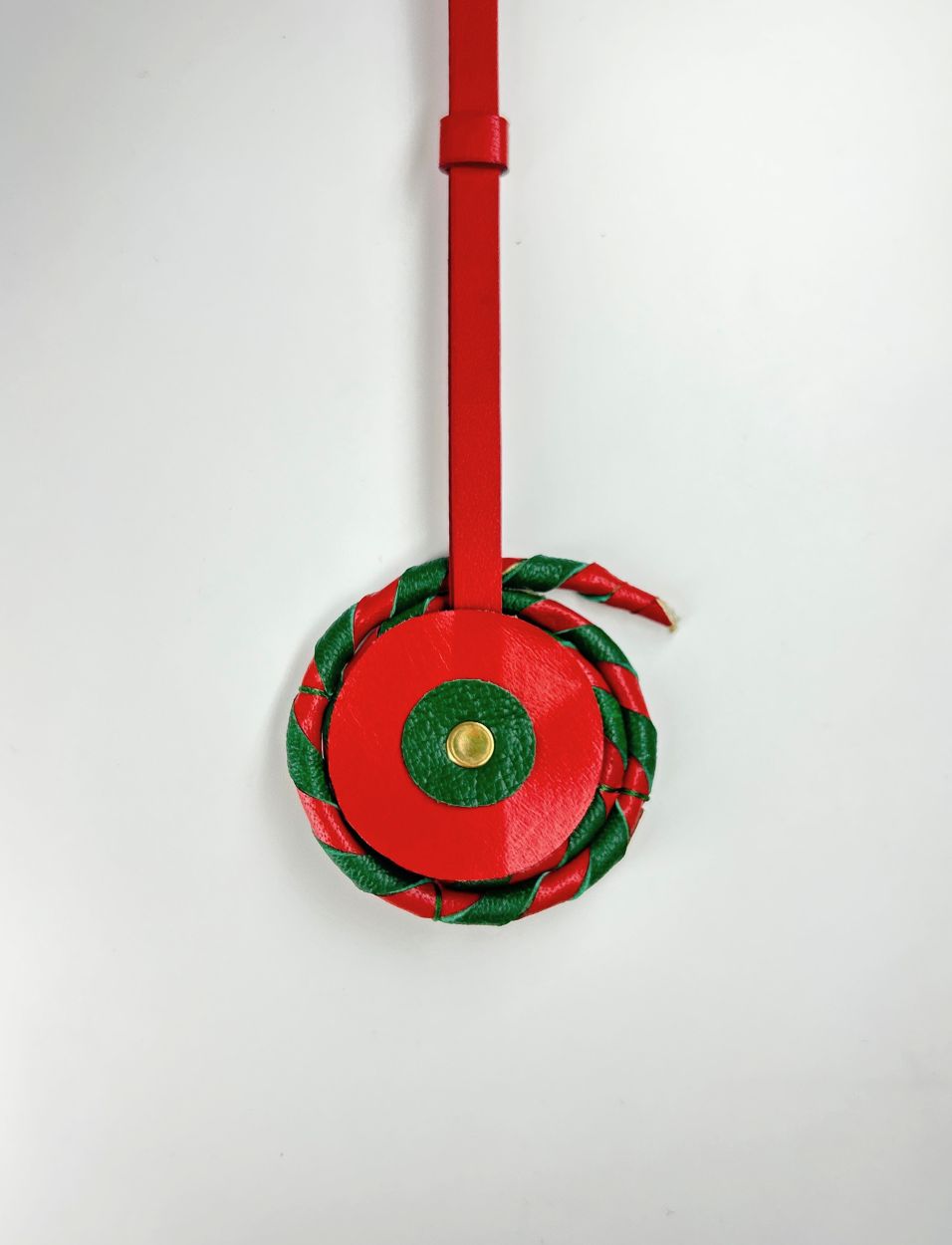 Red and green leather chakri charm with gold accent on white background