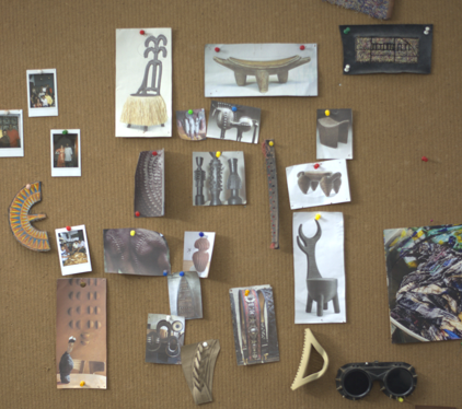Collection of various items pinned to a corkboard, including photographs and small sculptures.