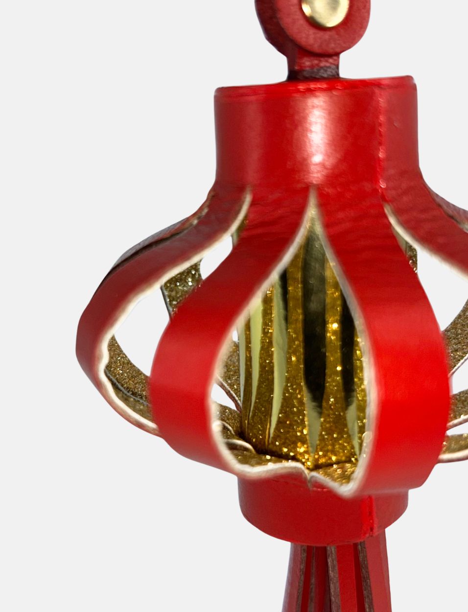 Close-up of red decorative Chinese lantern with gold glitter details on white background