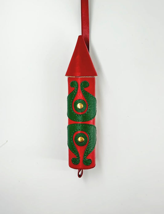 Red rocket-shaped leather charm with green embossed decorative patterns and gold studs on white background